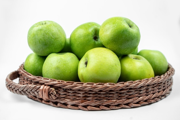 Groep rijpe groene appels in een mand op witte ondergrond