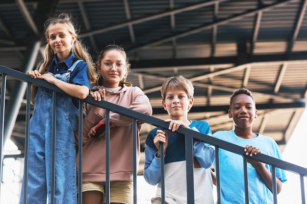 Groep schattige multiculturele vrienden in vrijetijdskleding die bij de reling staan