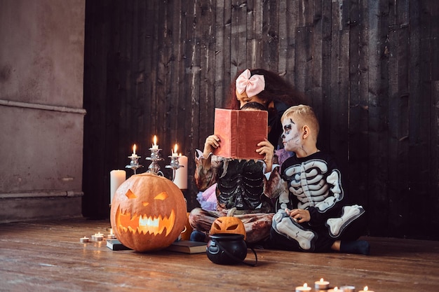 Groep schattige multiraciale kinderen in enge kostuums die horrorverhalen lezen in een oud huis, tijdens Halloween-feest. Halloween-concept.
