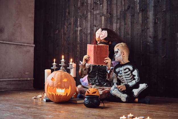 Groep schattige multiraciale kinderen in enge kostuums die horrorverhalen lezen in een oud huis, tijdens halloween-feest. halloween-concept.