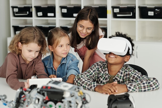 Groep schoolkinderen die bij het bureau zitten terwijl een van hen een presentatie maakt