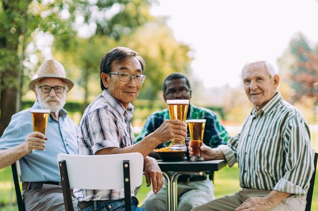 Groep senior vrienden die een biertje drinken in het park. Leefstijlconcepten over anciënniteit en derde leeftijd