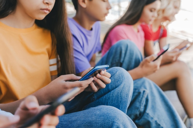 Groep serieuze multiraciale tieners met mobiele telefoons die online videocommunicatie bekijken