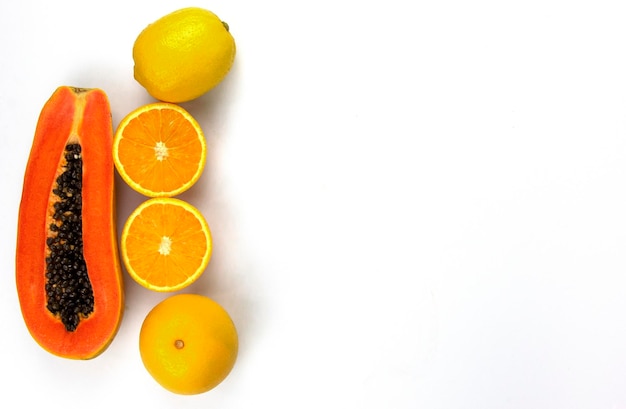 Groep sinaasappels en papaja gesneden met zoete druiven geïsoleerd op een witte achtergrond plaats aan de linkerkant