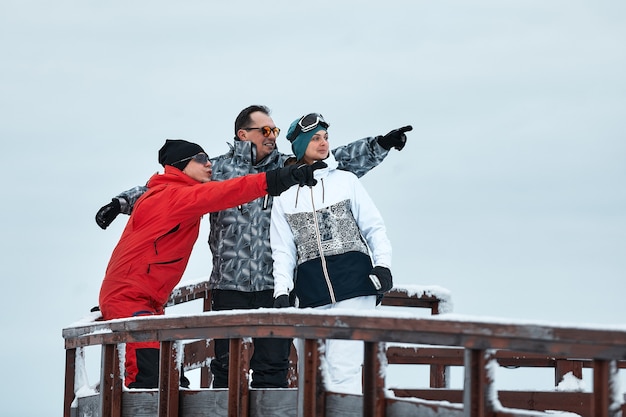 Groep skiërs vrienden op de berg rusten en drinken koffie uit een thermoskan op de achtergrond van de skilift