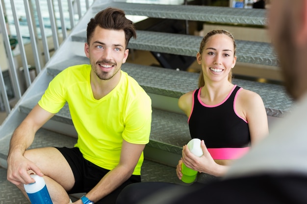 Groep sportieve mensen ontspannen en praten na de les in de sportschool.