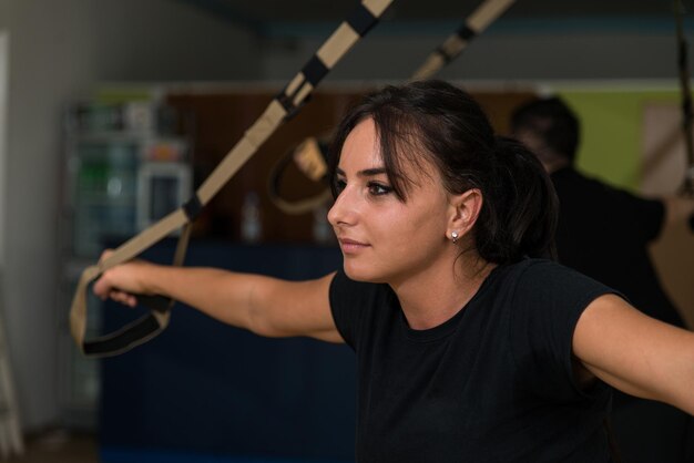 Groep sportmensen traint met Trx-fitnessbanden in de sportschool