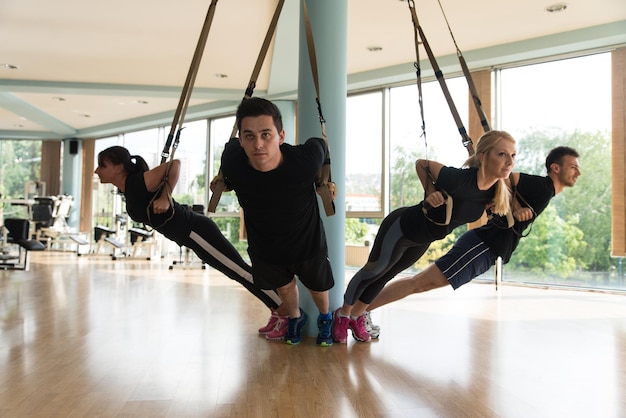 Groep sportmensen traint met Trx-fitnessbanden in de sportschool