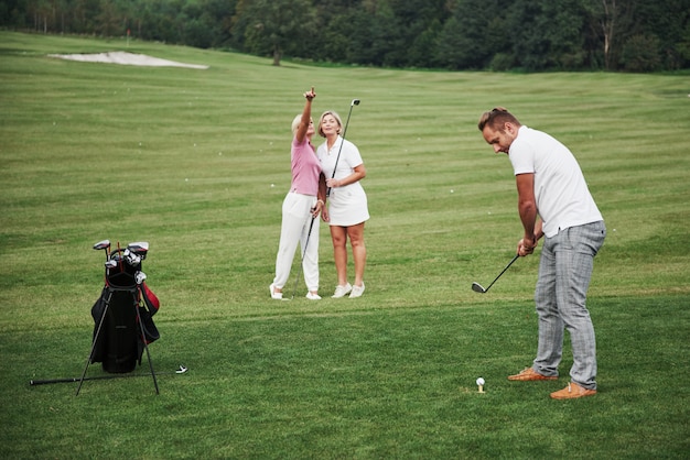 Groep stijlvolle vrienden op de golfbaan leren een nieuw spel te spelen