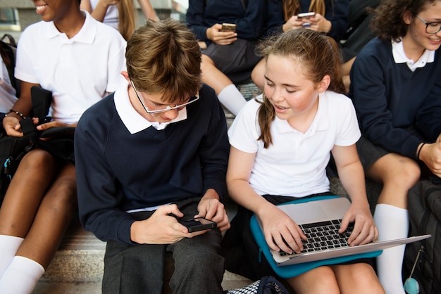 Groep studenten die bij treden zitten en digitale apparaten met behulp van