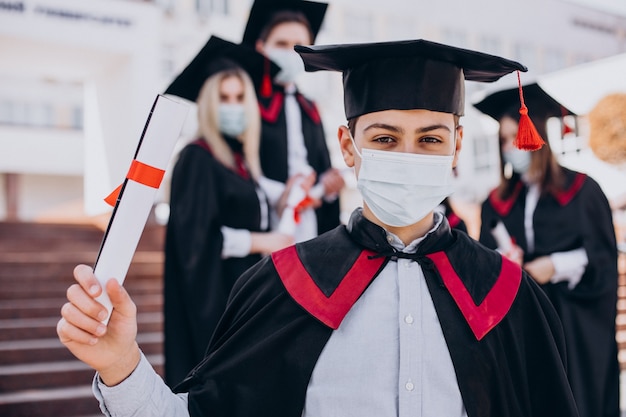 Groep studenten die samen afstuderen vieren en gezichtsmaskers dragen