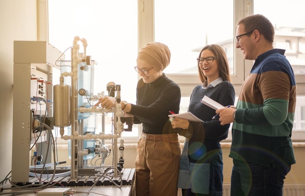 Groep studenten die technische beroepspraktijken doen met jonge vrouwelijke moslimleraar in het elektronische klaslokaal, onderwijs en technologieconcept