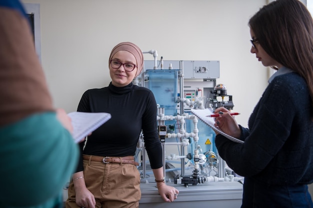 Groep studenten die technische beroepspraktijken doen met jonge vrouwelijke moslimleraar in het elektronische klaslokaal, onderwijs en technologieconcept