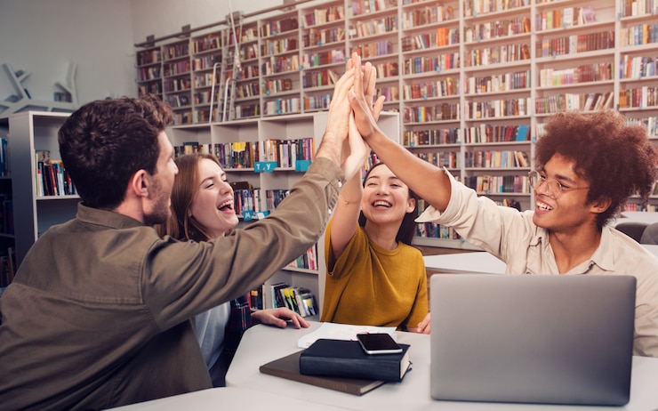 Foto groep studenten geeft high five in de bibliotheek