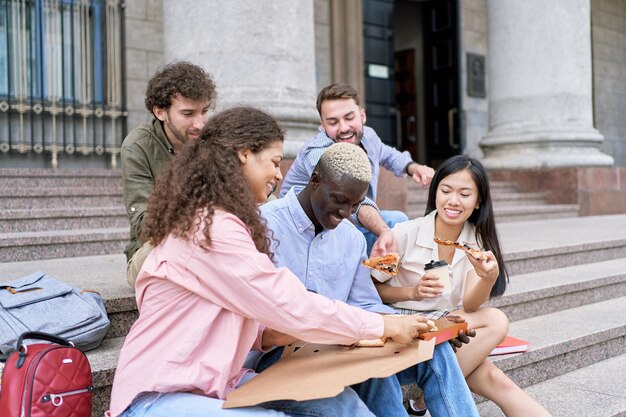 Groep studenten kijken naar een hete pizza in een doos