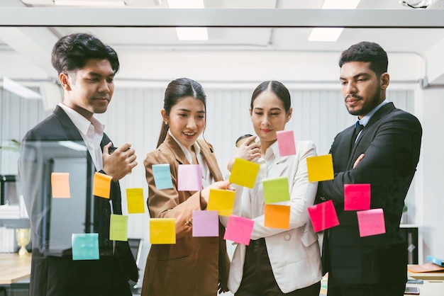 Groep succesvolle Aziatische zakenlieden teamwork Brainstorm vergadering met plaknotities op de glazen wand voor nieuwe ideeën Agile methodologie gebruiken voor zaken in een tech startup-kantoor