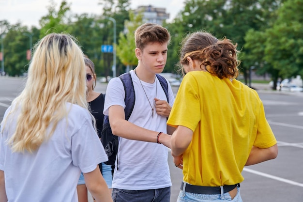 Groep tieners in de stad, serieuze kerel die met een vriend praat