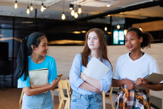 Groep tienerstudenten die lopen om te leunen in de bibliotheek van de school Universiteitsbibliotheekonderwijs en studentenleerconcept