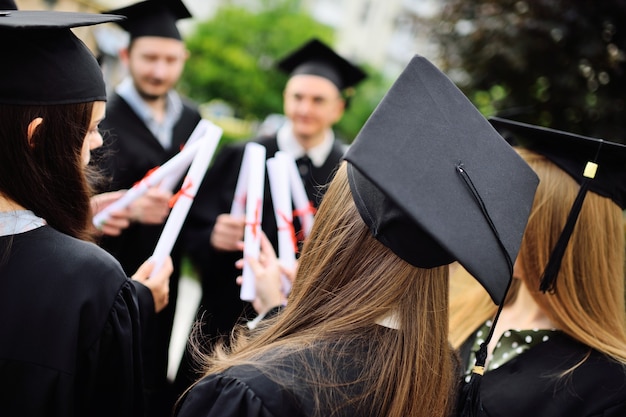 Groep universitair afgestudeerden in studentengewaden of mantel en vierkante hoeden bij de diploma-uitreiking...