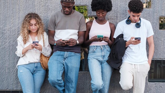 Groep universiteitsstudenten die met serieuze gezichten naar hun smartphones kijken Concepttechnologieverslaving jeugd