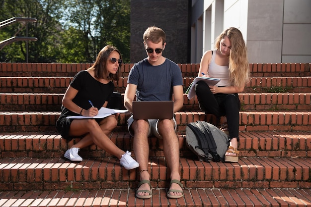 Groep universiteitsstudenten die zittend op de trap werken