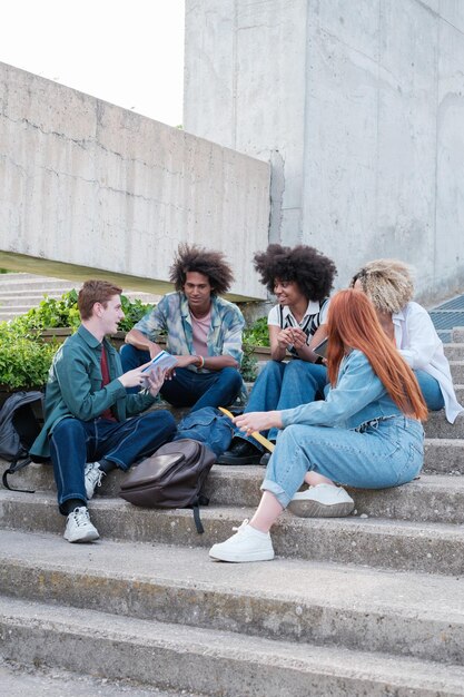 Groep universiteitsstudenten zittend op een trap van het college in de open lucht Concept onderwijs vriendschap samen