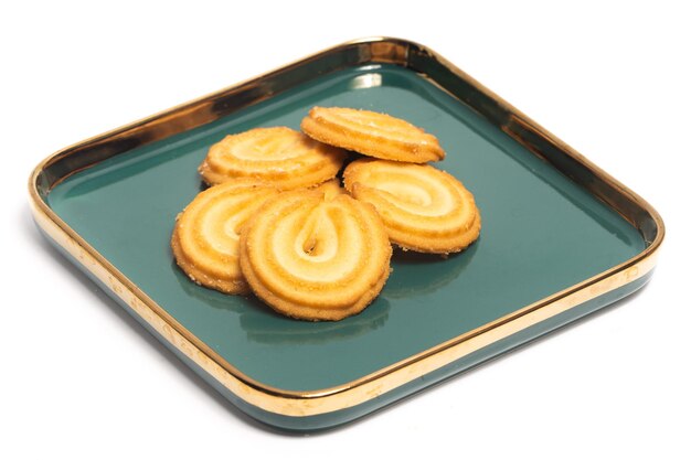 Groep van Deense boterkoekjes het vanille ringkoekje in een groen bord geïsoleerd op een witte achtergrond