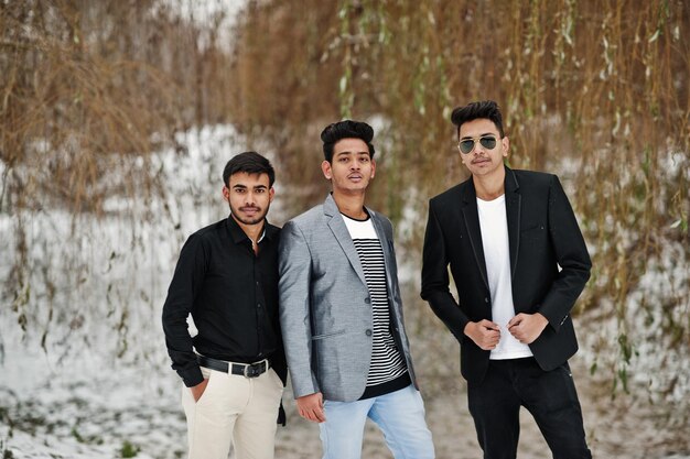 Groep van drie casual jonge Indiase mans geposeerd op winterdag