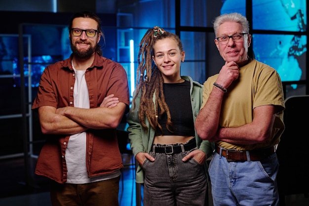 Groep van drie gelukkige IT-ingenieurs in vrijetijdskleding die naar de camera kijken