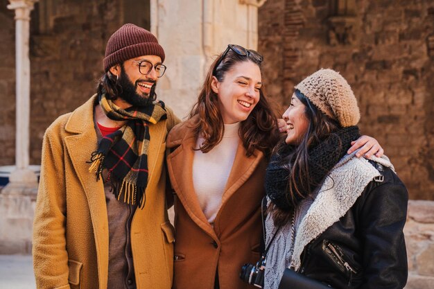 Groep van drie gelukkige multiraciale toeristische vrienden die samen plezier hebben op een weekendreis Jonge mensen lopen en glimlachen buiten en knuffelen elkaar Vakantie concept Hoogwaardige foto