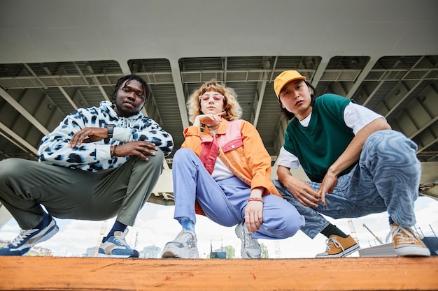 Groep van drie jonge mensen die straatkleding buiten dragen terwijl ze op de trap zitten in de stad a
