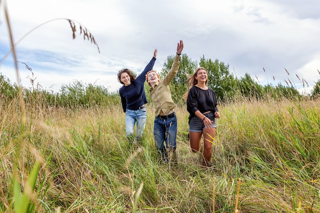 Foto groep van drie vriendenjongen en twee meisjes die en samen buiten plezier hebben