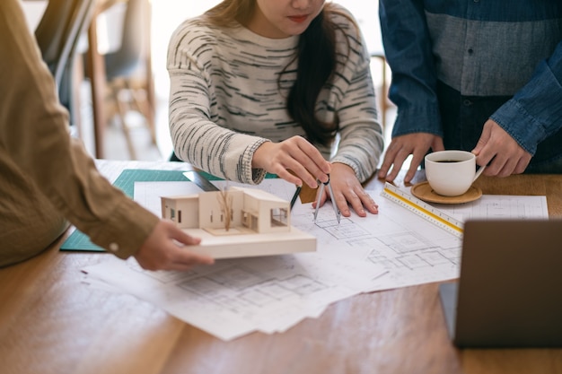 Groep van een architect die werkt en schaal meet van een massamodel op tafel in kantoor