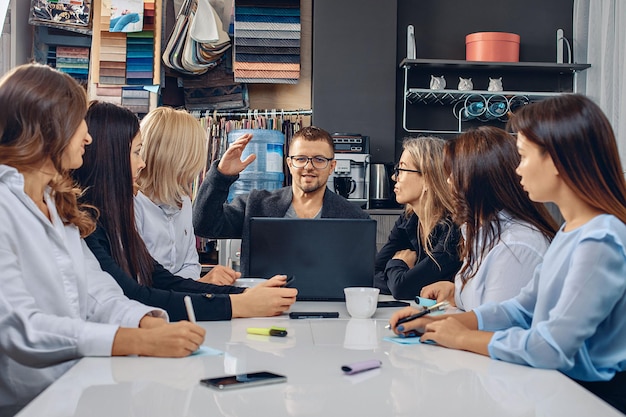 Groep van geconcentreerde communicatieve en ondergedompelde werknemers die in een creatieve omgeving werken en projecten bespreken en analyseren. 6 meisjes en 1 man. Productiviteitsconcept