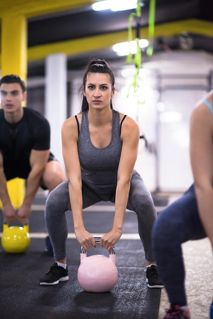 groep van gezonde jonge atleten doen oefeningen met kettlebells op cross fitness-studio