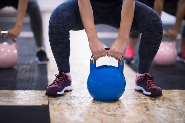 groep van gezonde jonge atleten doen oefeningen met kettlebells op cross fitness-studio