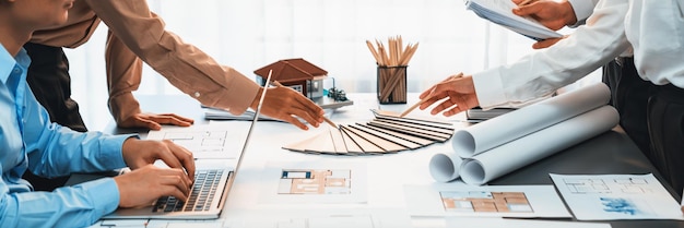 Groep van interieurontwerpers in een vergadering met ingenieurs over interieurontwerp en planning voor het huisproject blauwdruk en model het kiezen van kleurmonster en mood board materialen Inzicht