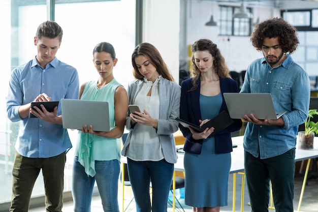 Groep van leidinggevenden met behulp van digitale tablet, mobiele telefoon en laptop