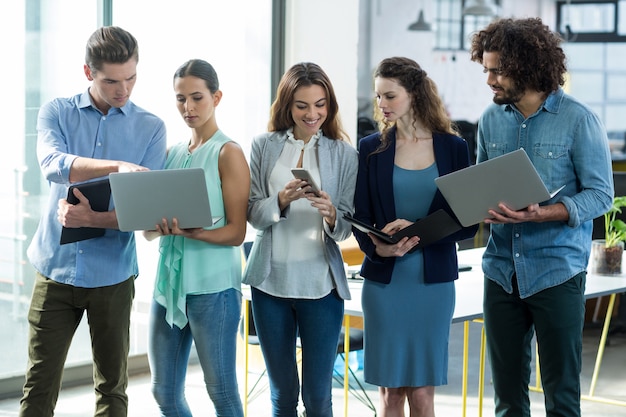 Groep van leidinggevenden met behulp van digitale tablet, mobiele telefoon en laptop