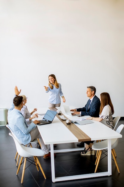 Groep van mensen uit het bedrijfsleven met jonge volwassenen en senior vrouw collega over bijeenkomst in het moderne, lichte kantoor interieur