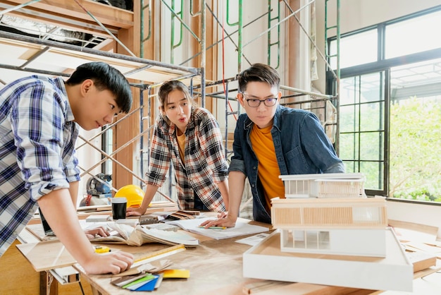 Groep van slimme aziatische architecten interieurontwerpteam overleg met constction engineer werk brainstrom ontmoeting met huis project blauwdruk en home mockup in huis renovatie structuur achtergrond