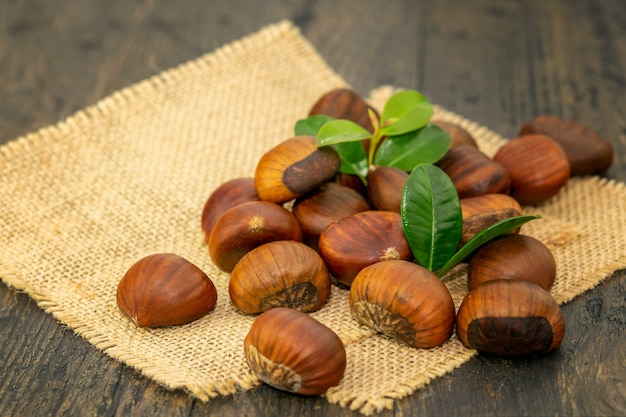 Groep van verse rijpe kastanjes op de rustieke zak en op de natuurlijke houten achtergrond.