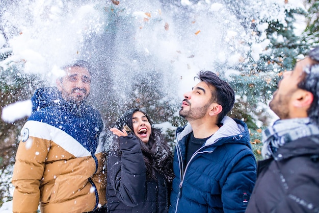 Groep van vier indiaan die plezier heeft in het buiten spelen in de sneeuw tijdens het doorbrengen van Chrisymas-vakanties