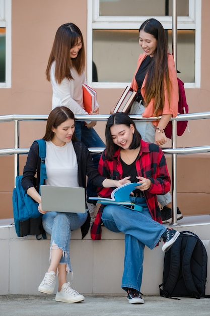 Groep van vier jonge, aantrekkelijke Aziatische meisjesstudenten die samen studeren op de universiteitscampus buiten. Concept voor onderwijs, vriendschap en studentenleven.