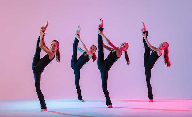 Groep van vijf tieners balrins in zwarte nauwsluitende kostuums dansen moderne konteporari op al