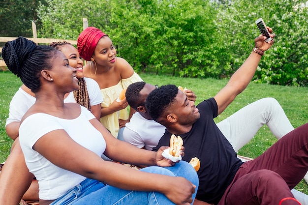 Groep van vijf vrouwelijke en mannelijke vrienden die selfie op camera-smartphone nemen en plezier hebben in de buitenlucht in de buurt van het meer