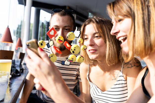 Groep van vrolijke vrienden kijken naar het telefoonscherm en enkele foto's afkomstig van de telefoon