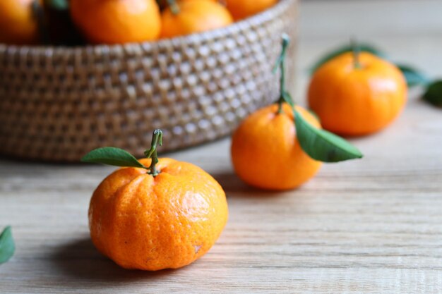 Groep vers mandarijnfruit met bladeren in de rotanmand op de houten tafel