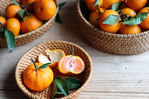 Groep vers mandarijnfruit met bladeren in de rotanmand op de houten tafel