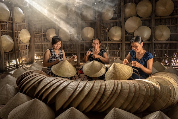 Groep vietnamese vrouwelijke vakman die de traditionele hoed van vietnam maakt